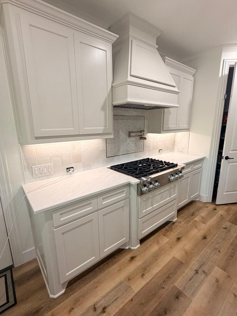 Remodeled kitchen with painted cabinets, range hood and quartzite counters