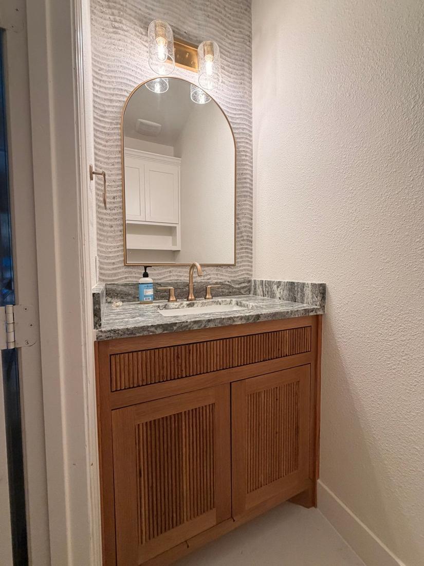 Powder bath with fluted wood vanity and arched mirror
